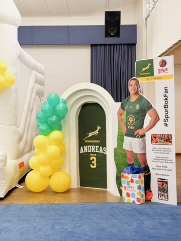 Close-up of white arch with green, yellow and blue balloon garland