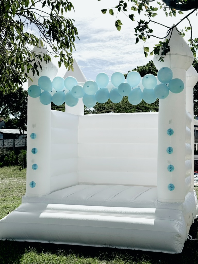 Classic all-white jumping castle styled with a blue balloon garland