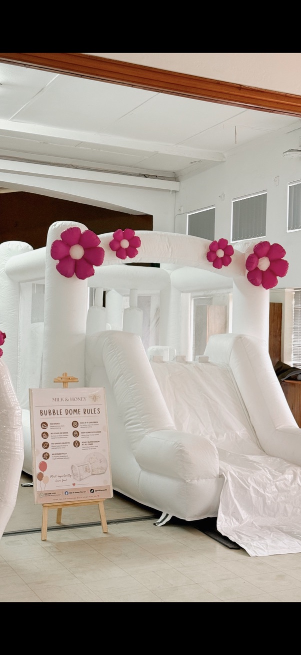 Bubble dome bounce house decorated with pink flower balloons